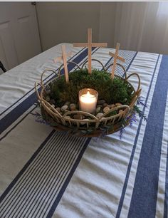 a candle is lit in a basket with moss and crosses on the tablecloths