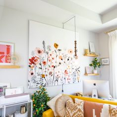 a living room with yellow couches and pictures on the wall above them, along with other decor items