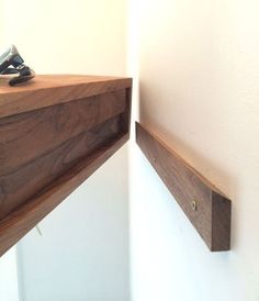 a cell phone is sitting on top of a wooden shelf next to a white wall