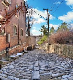 an old cobblestone street with stone steps leading up to a brick building in the background