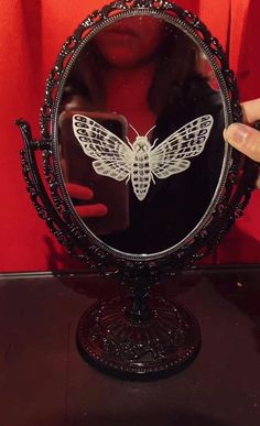 a person holding up a mirror with a butterfly on it