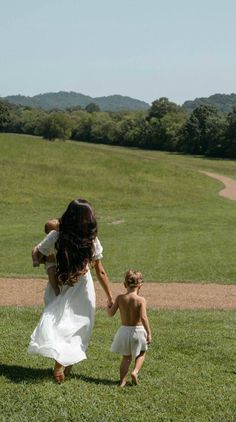 a woman and child walking in the grass