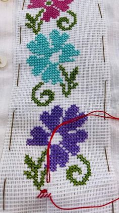 a close up of a piece of cloth with flowers on it and some red thread