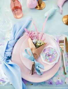 a table set with pink plates and blue napkins