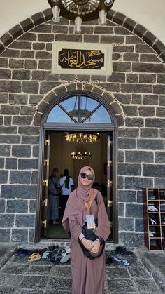 a man standing in front of a doorway wearing a hijab and holding a bag