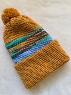 a knitted beanie with multicolored stripes and a pom - pom