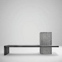 a concrete bench sitting on top of a white floor next to a tall cement block