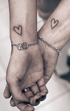 two people holding hands with tattoos on them