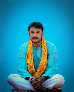 a man sitting on the ground wearing a yellow scarf