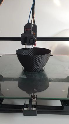 a black bowl sitting on top of a glass table next to a wire and wires