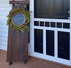 a wooden sign sitting in front of a door with a wreath on top of it