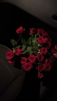 a bunch of red roses sitting in the back seat of a car with dark background