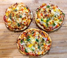 three small pizzas sitting on top of a wooden table