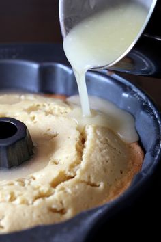 someone pouring batter on top of a cake in a pan