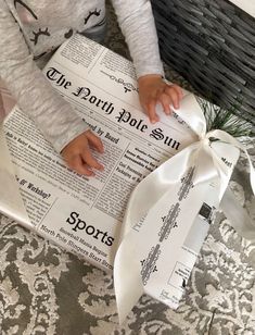 a young child holding onto a newspaper wrapped in white ribbon