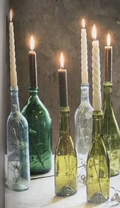 there are four bottles with candles in them