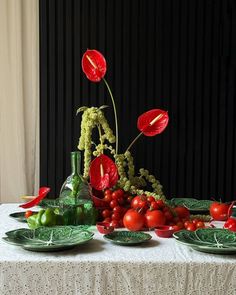 a table topped with green plates and red flowers