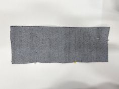 a piece of gray fabric with yellow stitching on the bottom and one half cut off