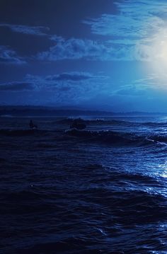 two surfers are riding the waves in the ocean under a full moonlit sky