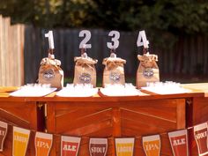 beer bottles are lined up on top of a wooden table with bunting around them