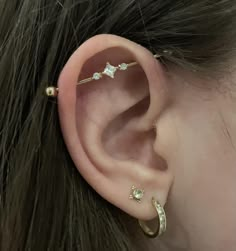 a woman's ear with three small stars attached to the back of her ear