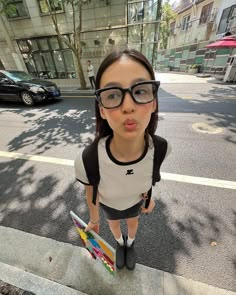 a woman with glasses standing on the sidewalk