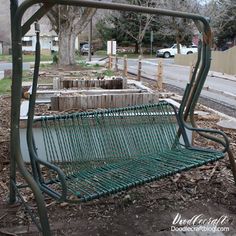 a green metal bench sitting on the side of a road