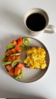 a breakfast plate with toast, kiwi and fruit on it next to a cup of coffee