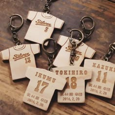 five wooden key chains with different sports jerseys on them and numbers printed on the tags