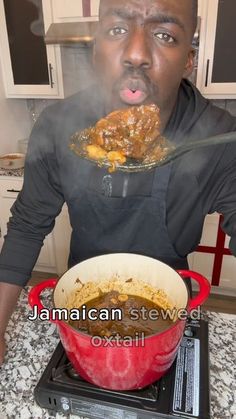 a man holding a plate with food on it in front of his face while sitting at the stove