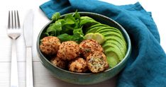 a bowl filled with meatballs and veggies next to a knife and fork