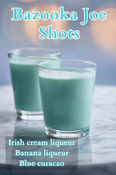 two glasses filled with green liquid sitting on top of a table