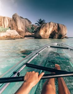 a person is sitting on a boat in the water near some large rocks and boulders