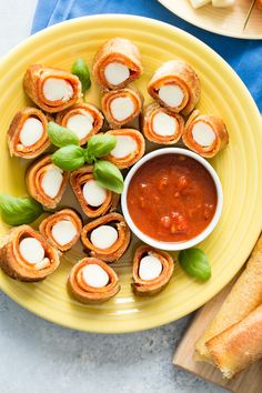 small appetizers are served on a plate with bread and tomato sauce in the bowl