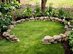 a garden with grass, rocks and flowers in the shape of a circle on top of it