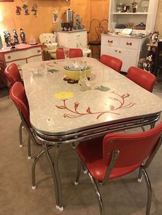 a dining room table with red chairs and a white counter top in the middle of it