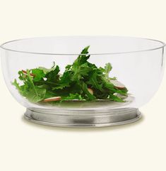 a glass bowl filled with lettuce on top of a table