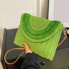 a person holding a green purse on top of a table