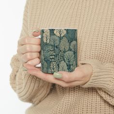 a woman holding a coffee mug in her hands with trees printed on the front and sides