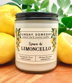 a jar of lemon scented candle sitting on top of a wooden table next to lemons