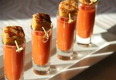 three glasses filled with food sitting on top of a white tray next to each other