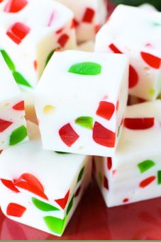 several pieces of white chocolate with red, green and pink designs on them sitting on a red plate