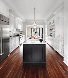 a large kitchen with white cabinets and wood flooring, along with stainless steel appliances