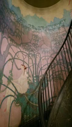 an artisticly painted wall with a spiral staircase leading up to the second floor area