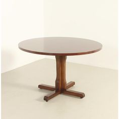 a round wooden table sitting on top of a white floor