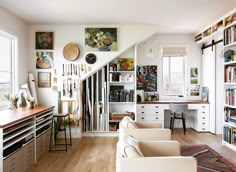 a living room filled with furniture and bookshelves next to a stair case in front of a window