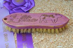 a wooden brush with the word hello written on it and a purple ribbon next to it