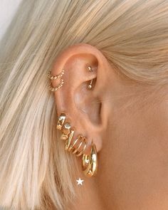 a woman with blonde hair wearing gold ear cuffs and piercings on her left ear