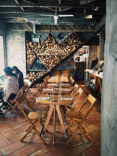 two people sitting at a table with chairs around it in front of a firewood rack