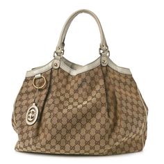 This is an authentic GUCCI Monogram Large Sukey Tote in Off White. This chic tote is crafted of classic brown on beige Gucci GG monogram canvas with an off white leather trim. The bag features rolled leather shoulder straps with light brass links and a top crest of leather with a hanging light brass Gucci interlocking GG logo charm. The top is open to a spacious brown fabric interior with a zipper pocket. Luxury Neutral Bags For Formal Occasions, Luxury Neutral Bags, Beige Monogram Canvas Bag With Double Handle, Beige Double Handle Monogram Canvas Bag, Classic Gucci Bag With Top Handle, Classic Monogram Canvas Bag With Handles, Designer Beige Bags With Gold-tone Hardware, Designer Beige Satchel With Double Handle, Beige Bags With Leather Handles For Everyday Luxury